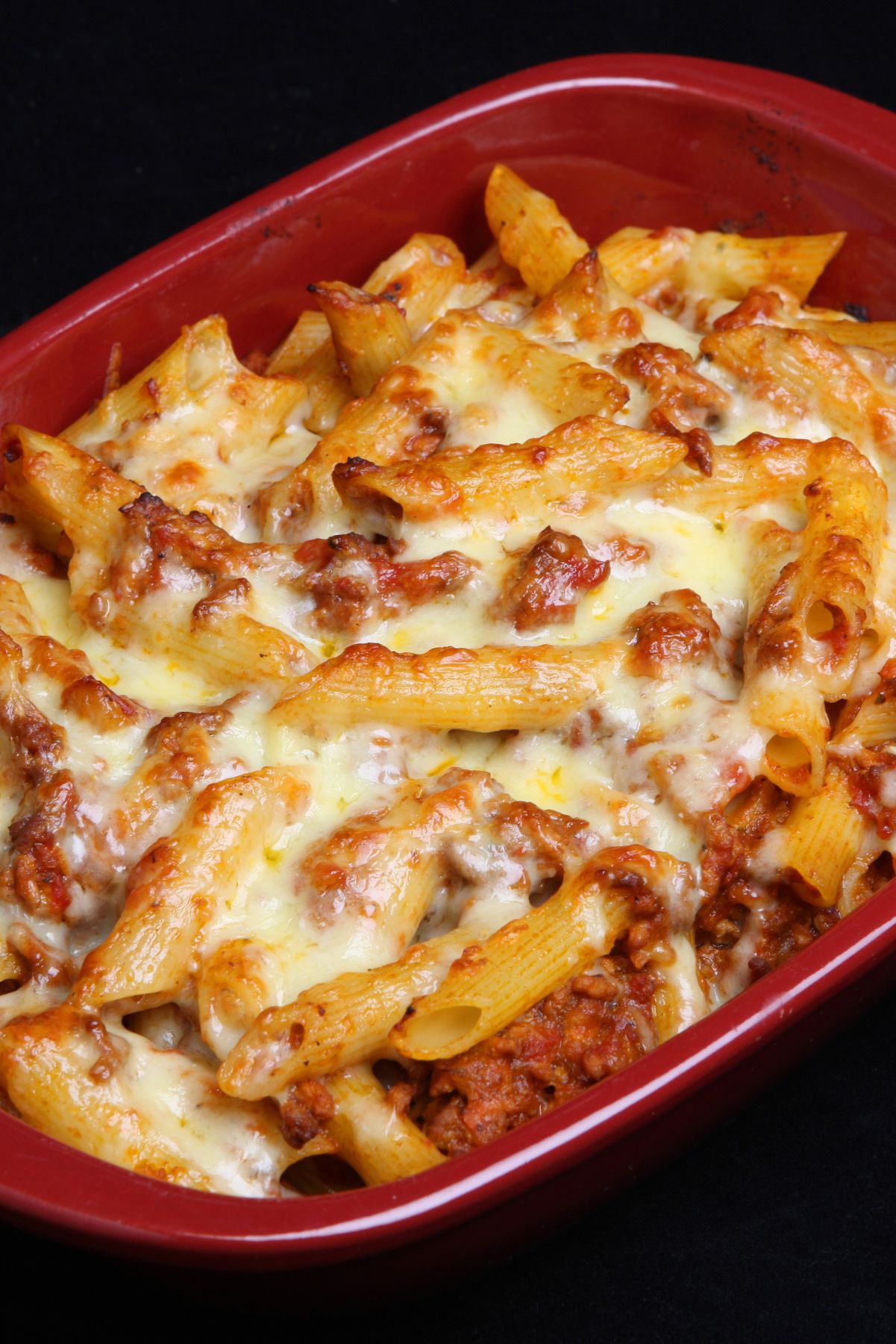 Weight Watchers Baked Ziti in a red casserole dish on a black background.