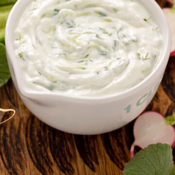 Closeup of Quick Weight Watchers Dill Dip in a white dish with radishes and celery around it.