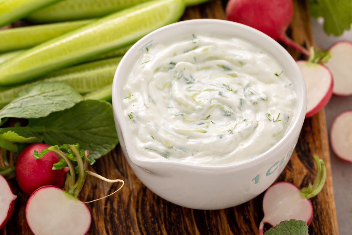 Quick Weight Watchers Dill Dip in a white dish, sitting on a wooden cutting board with fresh vegetables around it.