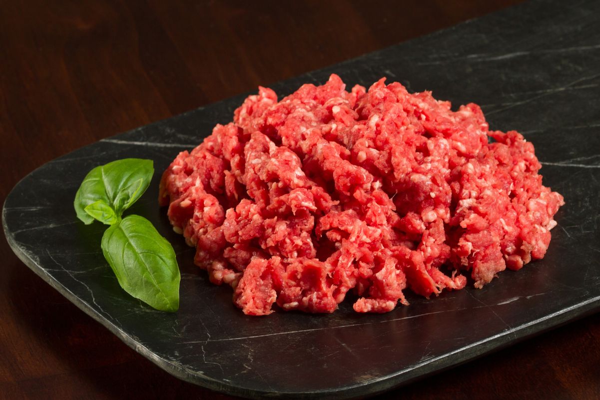 Raw ground beef on a black plate with a black bacground.
