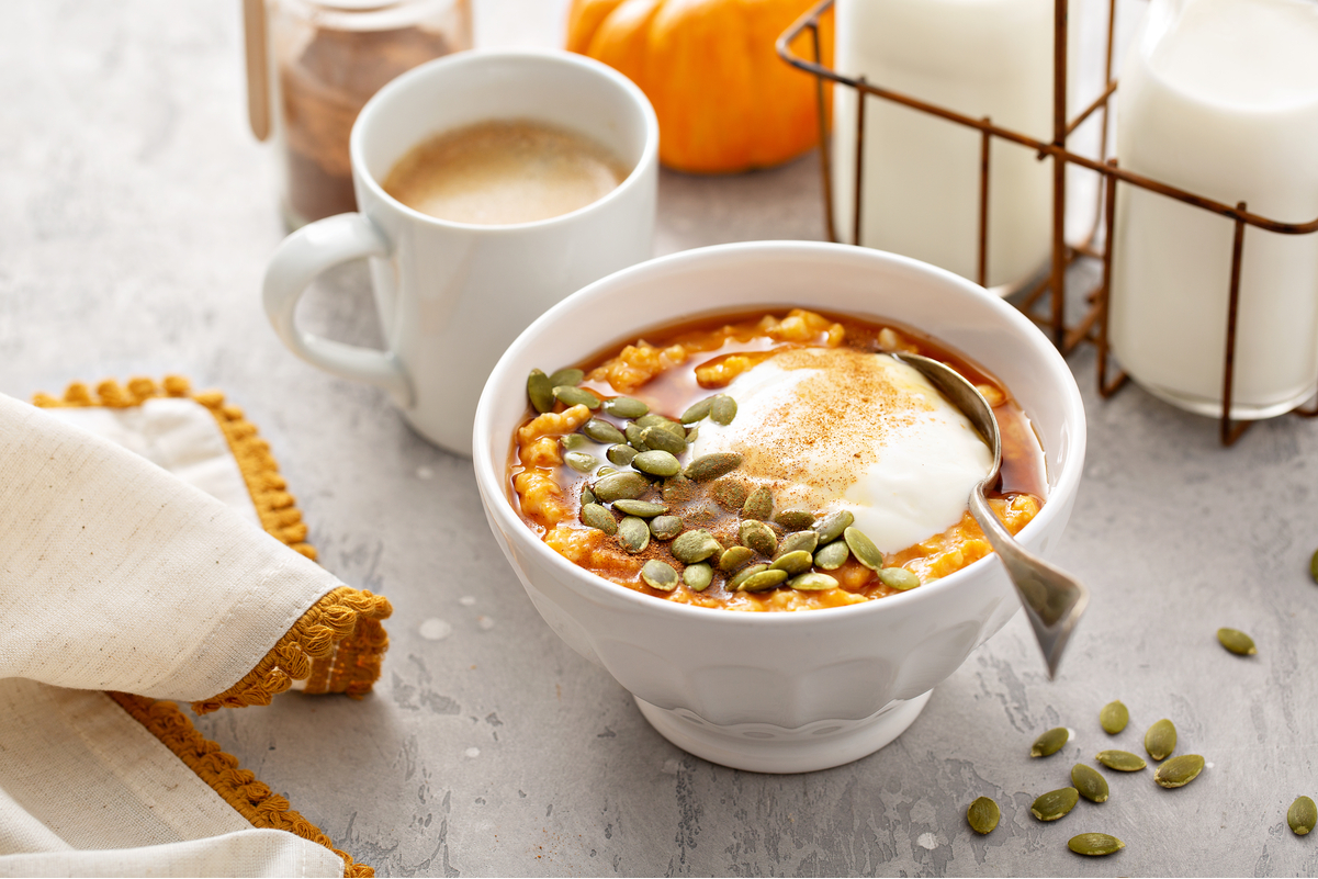 Weight Watchers Pumpkin Spice Oatmeal in a white bowl with a cup of coffee next to it.