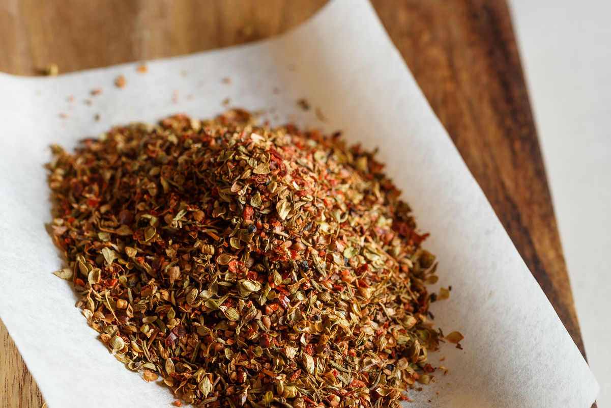 Closeup of Homemade Spicy Cajun Dry Rub (Weight Watchers) on a white piece of paper on a wooden surface.