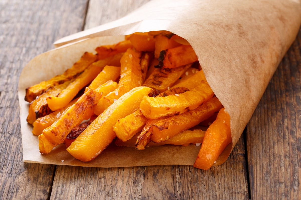 Easy Weight Watchers Baked Butternut Squash Fries wrapped in paper sitting on a rustic wooden surface.