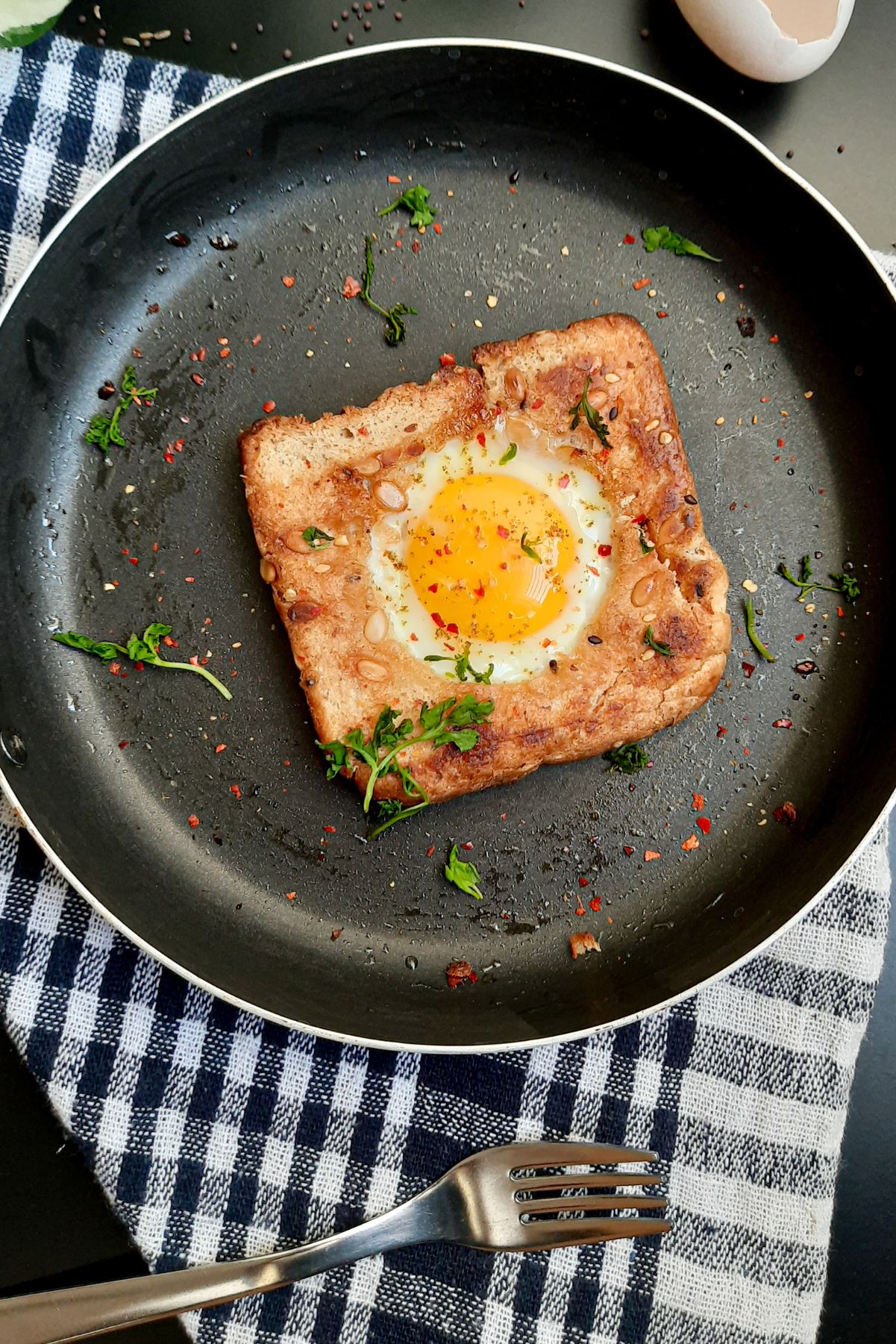 Weight Watchers Egg in a Nest in a skillet on a blue and white kitchen towel.
