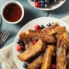Quick Weight Watchers French Toast Sticks (Air Fryer) on a white plate with berries. A small bowl of syrup next to it with a small bowl of berries.