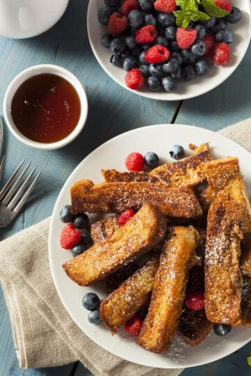 Quick Weight Watchers French Toast Sticks (Air Fryer) on a white plate with berries. A small bowl of syrup next to it with a small bowl of berries.