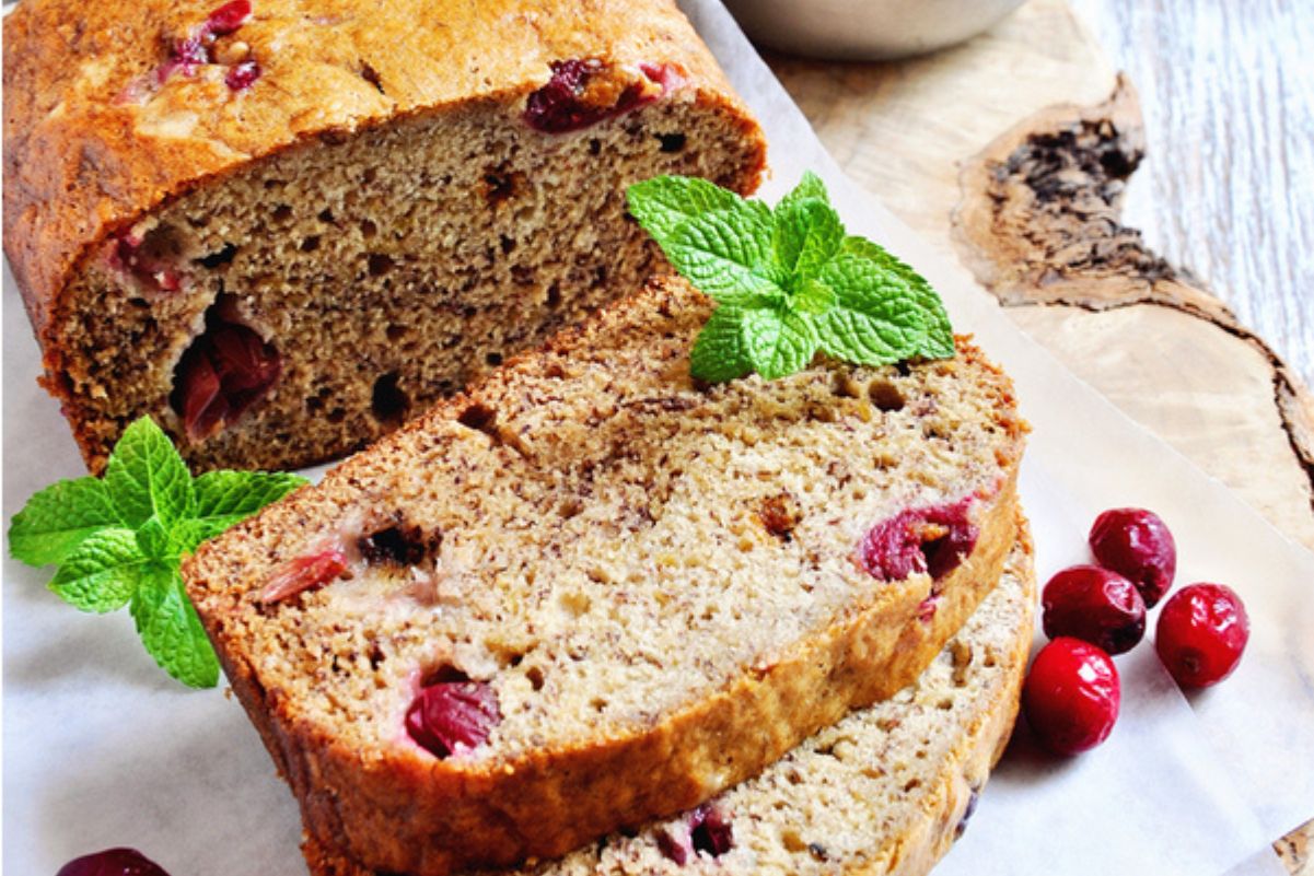 Easy Weight Watchers Cranberry Banana Bread half sliced on a cutting board with fresh cranberries.