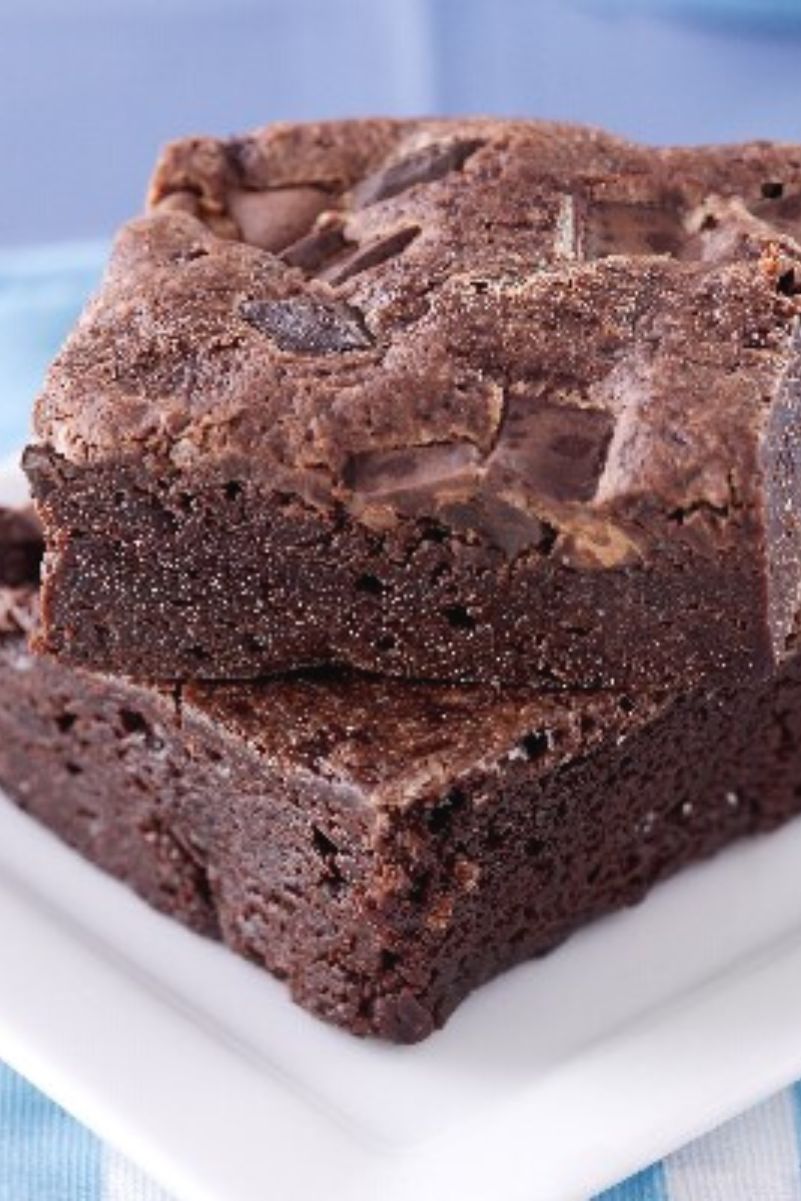 Closeup of 2 Weight Watchers Black Bean Brownies on top of each other sitting on a white plate, on a light blue cloth.