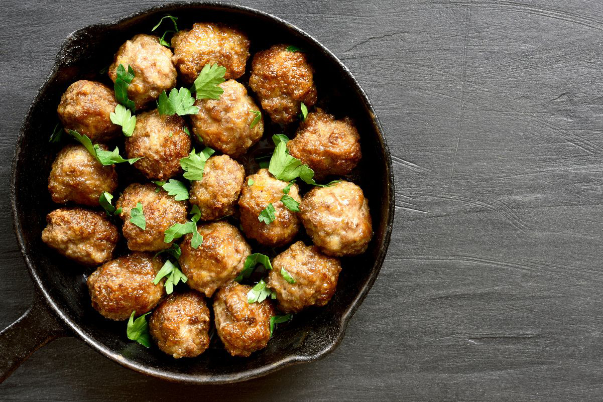 Mini Weight Watchers Italian Meatballs in a black skillet sitting on a gray surface.