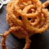 A pile of Air Fryer Weight Watchers Onion Rings on dark, slate surface.