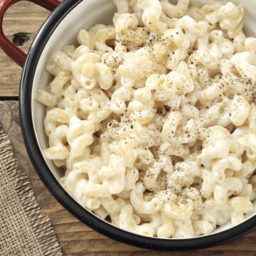 Overhead view of Weight Watchers Alfredo Macaroni in a red pot on a rustic wooden surface.