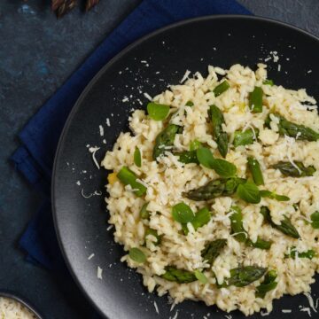 Overhead view of Weight Watchers Creamy Asparagus Risotto Recipe in a black bowl on a dark background.