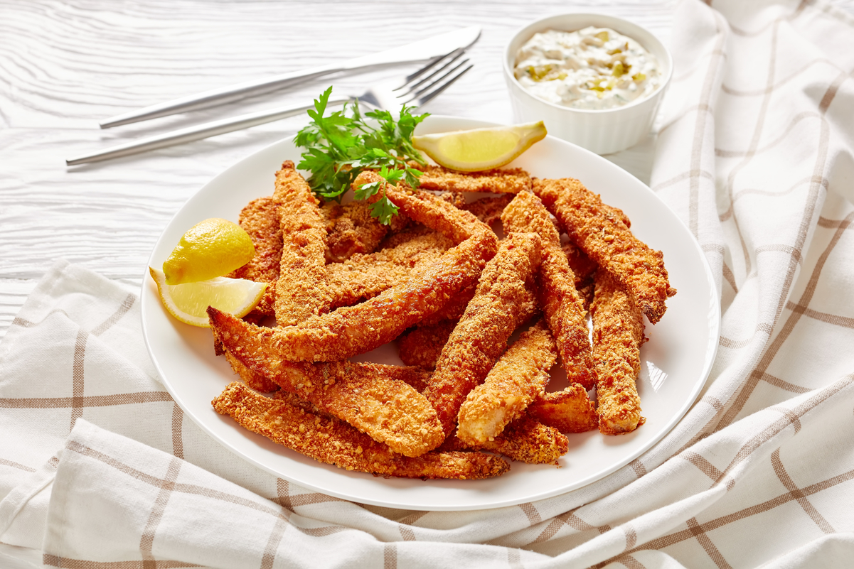 Weight Watchers Cornmeal Breaded Fish Fingers on a white plate with silverware in the background.