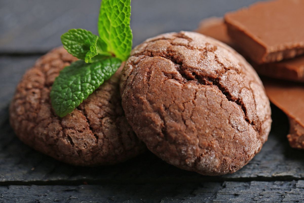 2 Easy Chocolate Fudge Cookies on a dark surface with chocolate next to them.