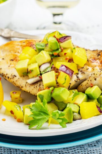 Closeup of Weight Watchers Grilled Chicken with Pineapple Avocado Salsa on a white plate.