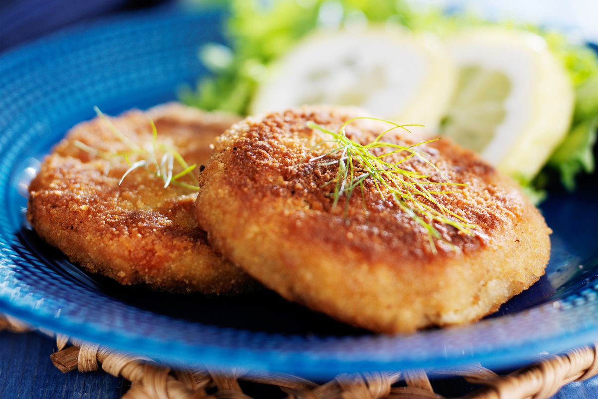 2 Weight Watchers Maryland Crab Cakes on a blue plate with a lemon and lettuce in the background.