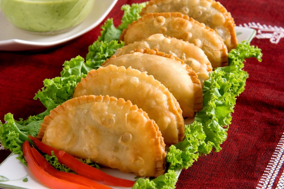 6 Weight Watchers Vegetarian Indian Samosa lined up on a rectangular, white plate that's lined with lettuce.