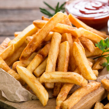 Closeup of Weight Watchers Baked Garlic & Herb Fries on a wooden cutting board.