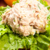 Closeup of a scoop of tuna salad on a bed of lettuce.