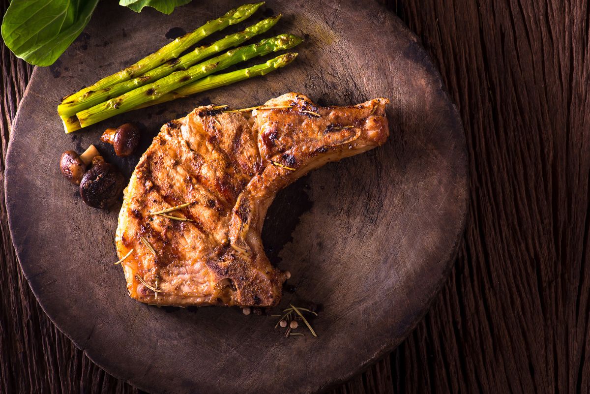 Overhead view of Weight Watchers Grilled Korean Pork Chop on a dark surface with asparagus.