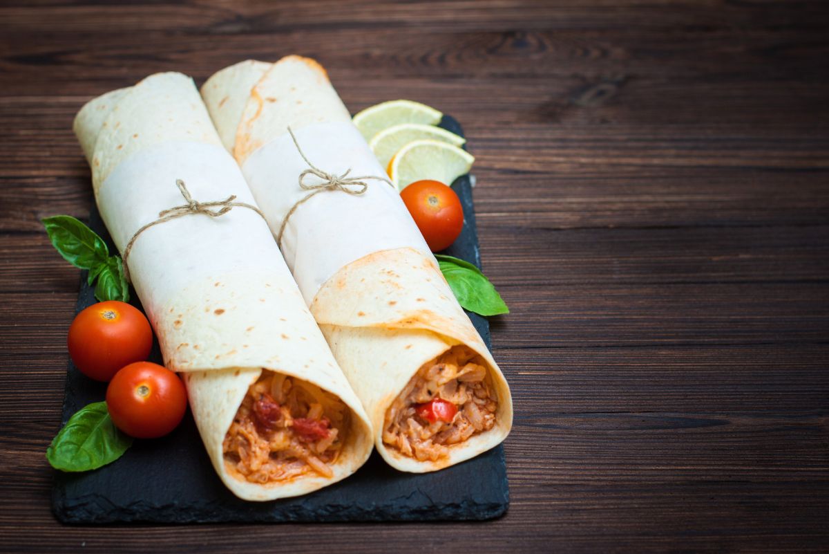 2 Weight Watchers Queso Chicken And Rice Wraps on a dark wooden surface.
