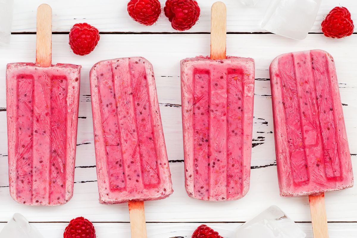 Overhead view of 4 Weight Watchers Raspberry Yogurt Popsicles on a light rustic surface.
