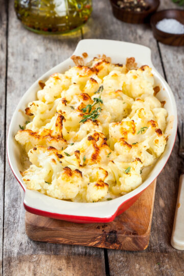 Weight Watchers Roasted Parmesan Cauliflower in a red and white casserole dish on a rustic, wooden surface.