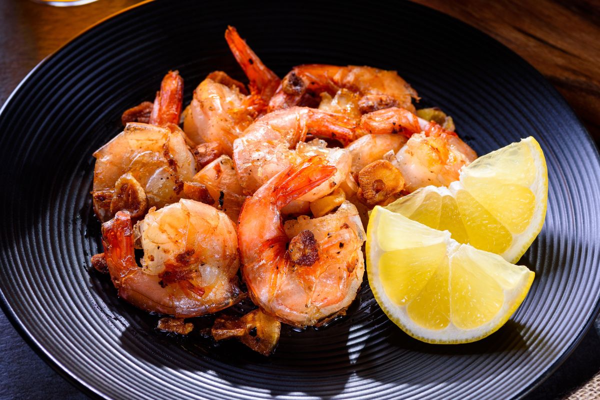 Weight Watchers Seared Garlic Shrimp on a black plate with a lemon wedge.