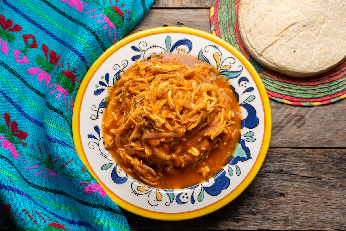 Overhead view of Weight Watchers Chipotle Chicken Tinga on a rustic wooden surface next to a blue cloth.