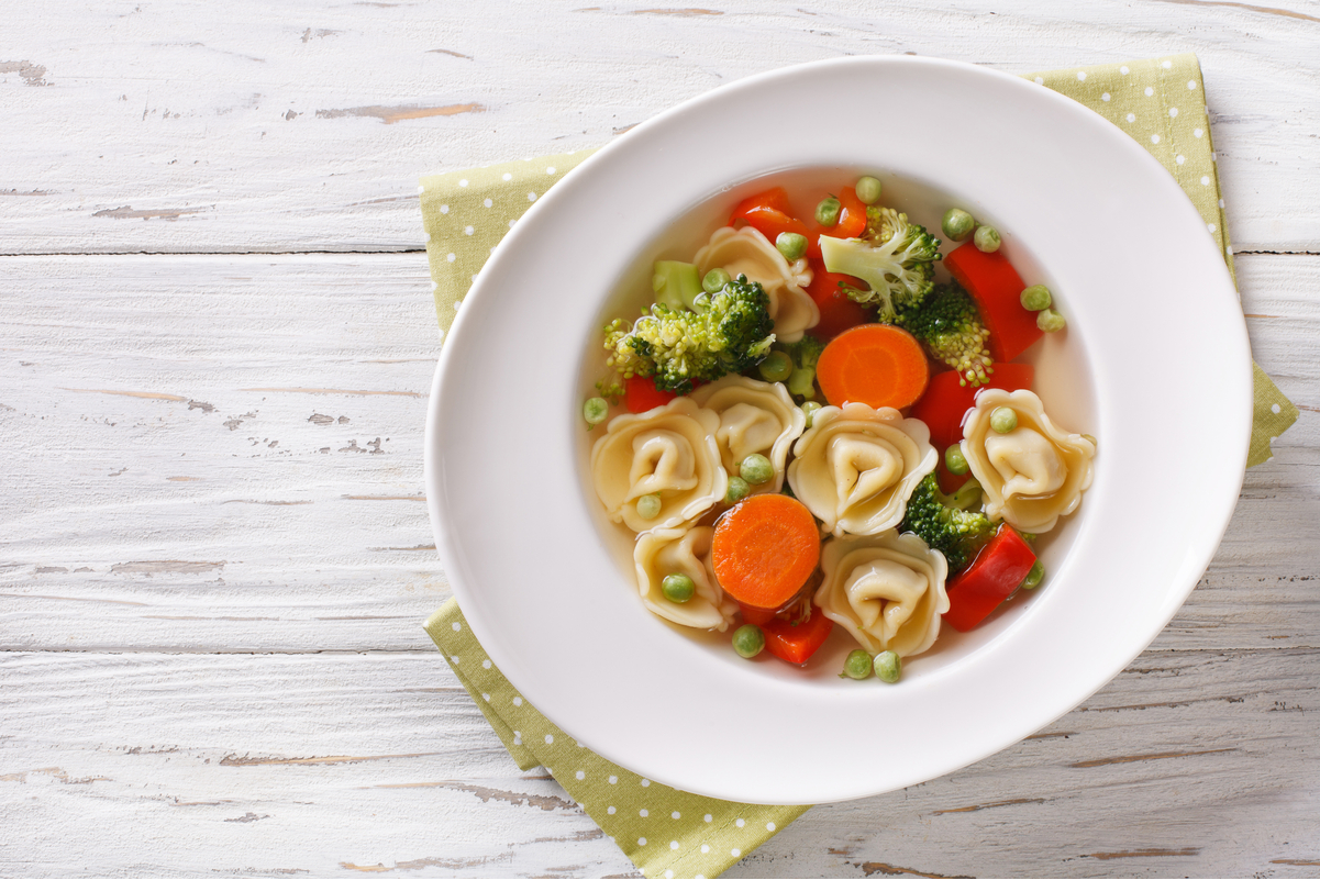 Weight Watchers Chicken and Tortellini Soup in a white bowl on a light rustic surface.