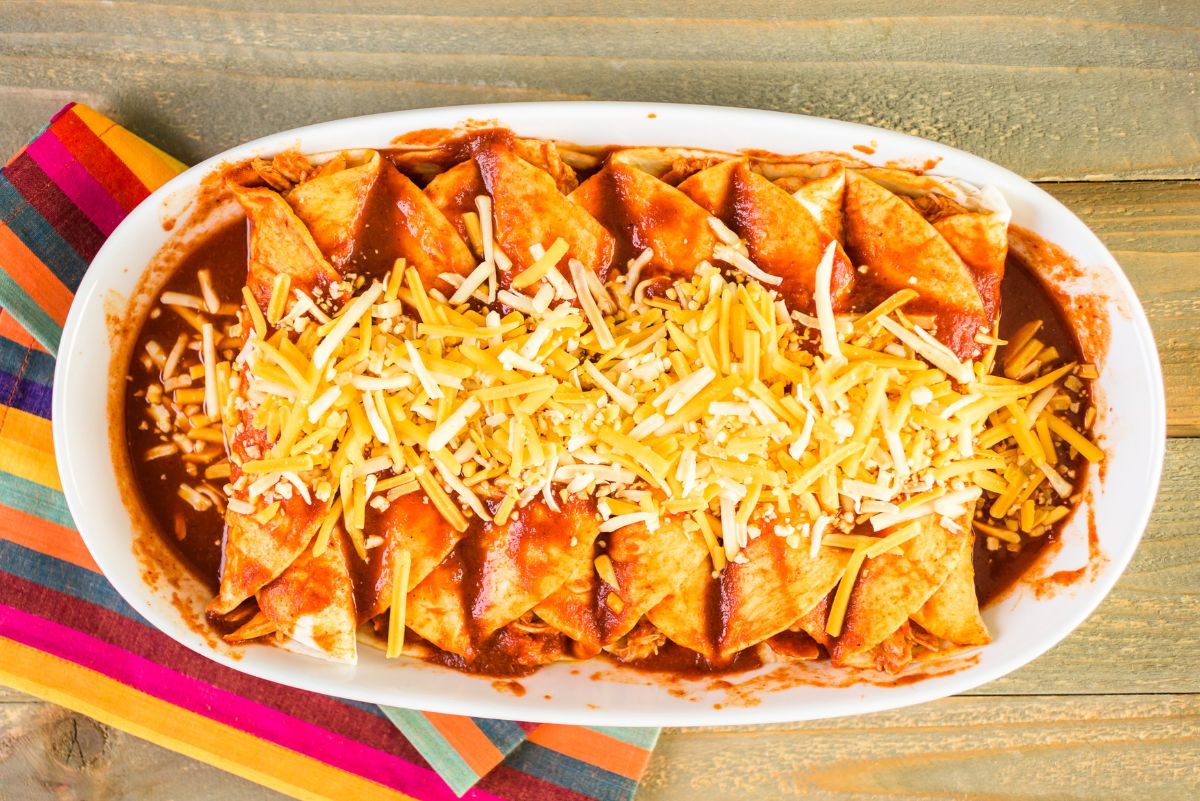 Weight Watchers Easy Turkey Enchiladas in a white casserole dish sitting on a colorful, striped dish towel.