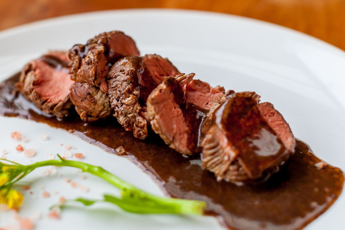 Sliced Weight Watchers Filet Mignon and Burgundy Wine Sauce on a white plate.