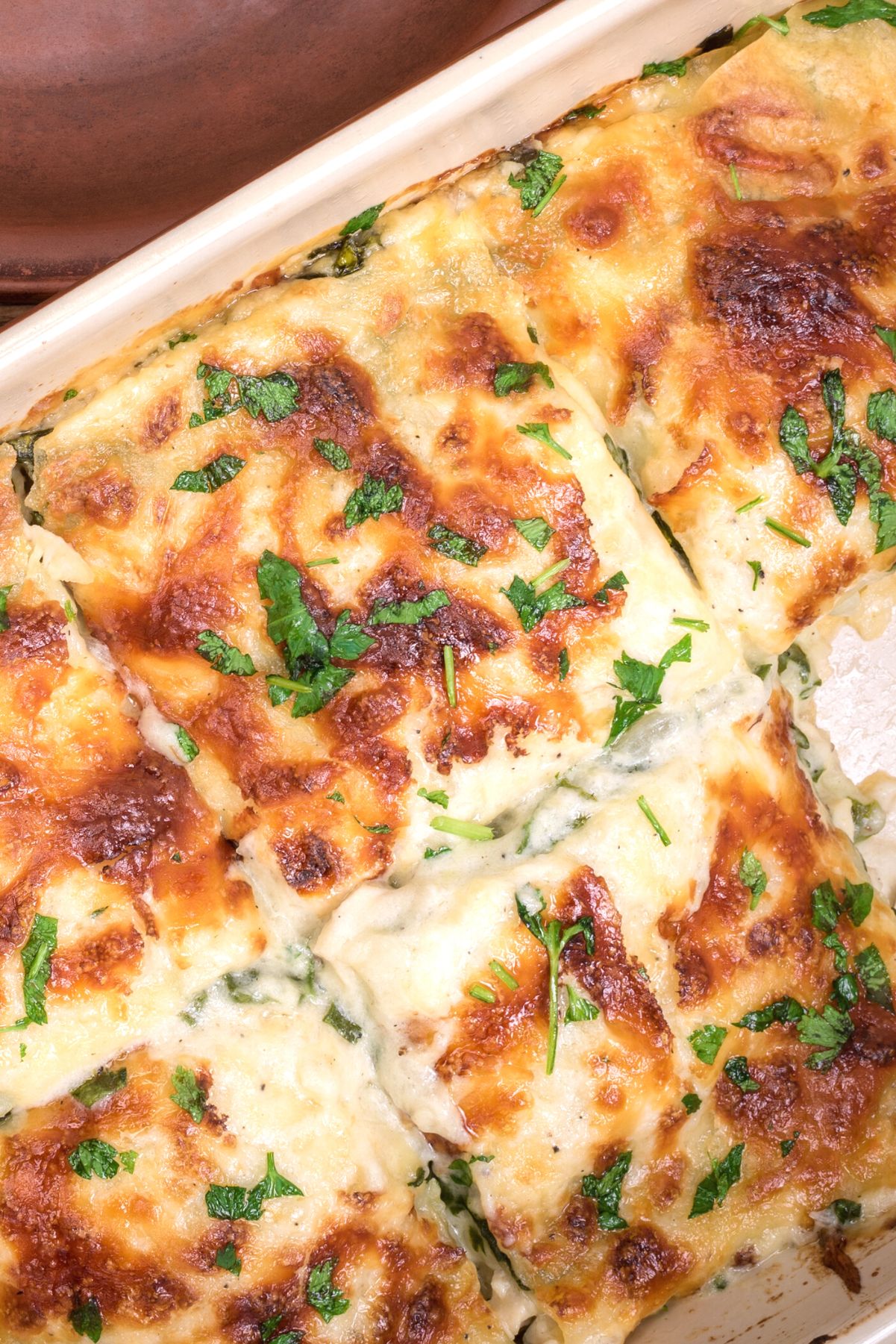 Closeup of Weight Watchers Ground Chicken Lasagna in a white casserole dish.