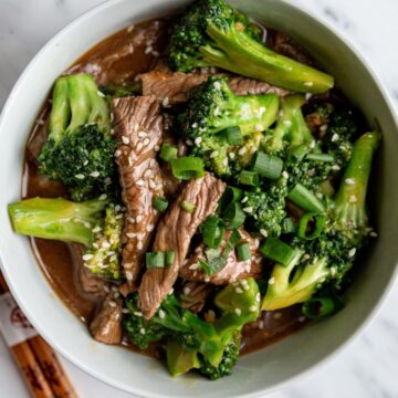 Overhead view of Weight Watchers Spicy Beef and Broccoli in a white bowl with chopsticks next to it.