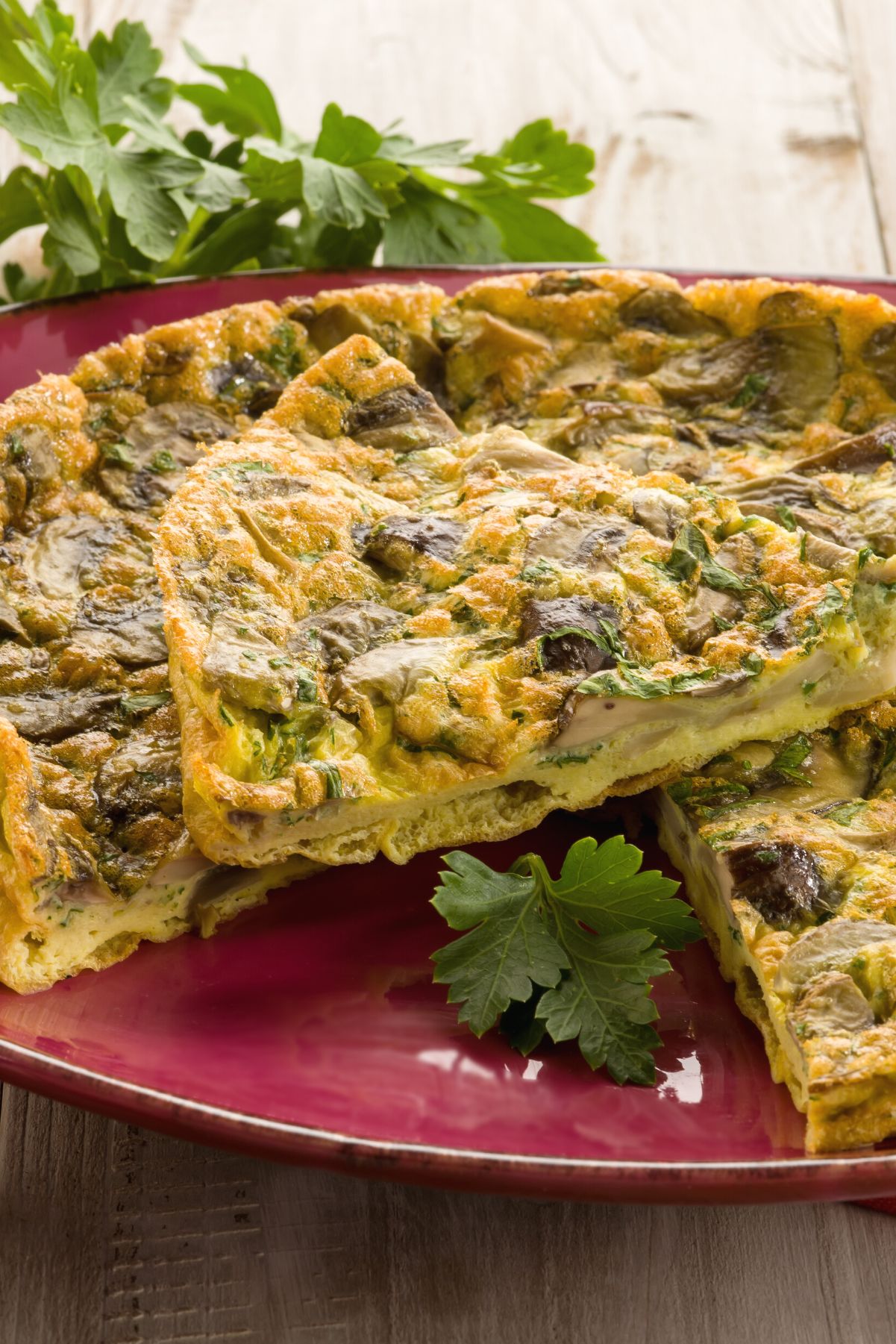 Weight Watchers Spinach Mushroom Quiche with one slice laying on top of it, sitting on a red dish.