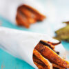 Closeup of Weight Watchers Cinnamon Sweet Potato Fries wrapped in white paper on a blue surface.