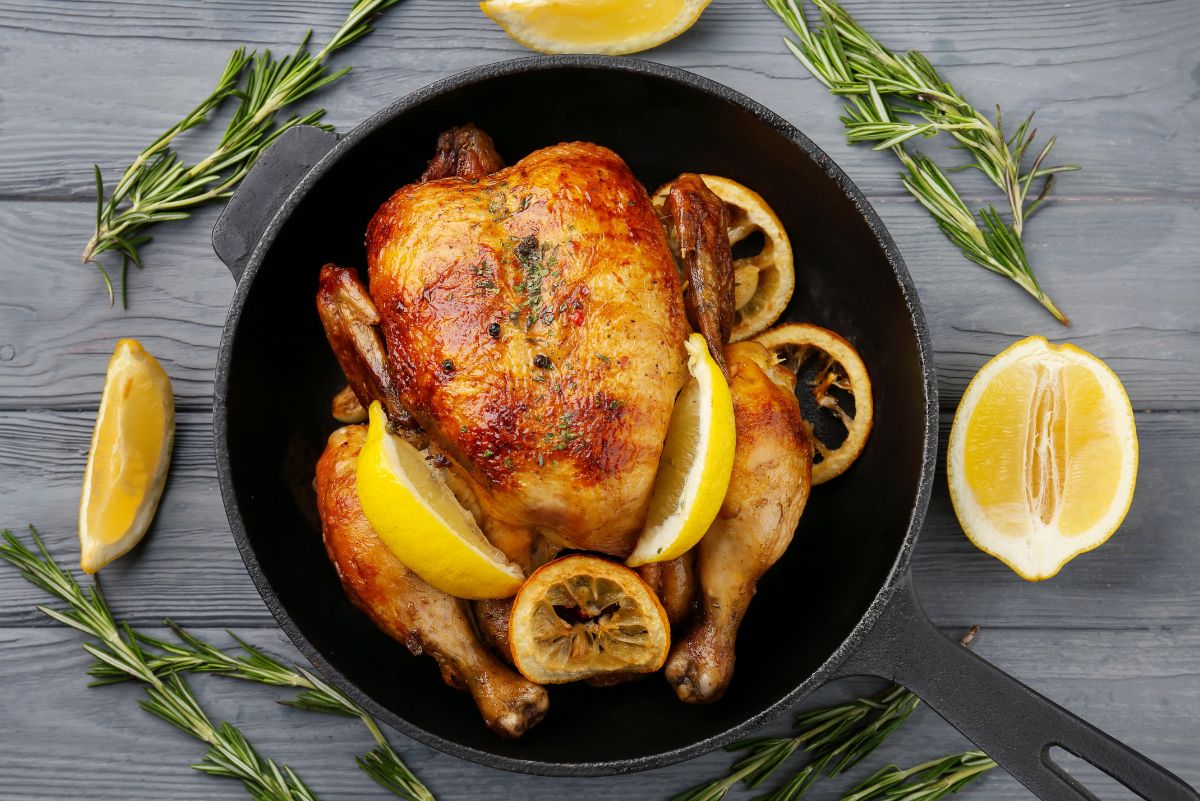 Overhead view of Weight Watchers Meyer Lemon Roast Chicken in a black pot surrounded by lemons.