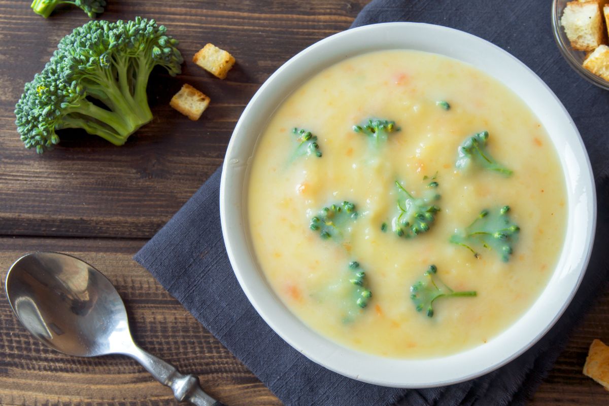 Weight Watchers Quick Broccoli Cheddar Soup in a white bowl sitting on a blue napkin.