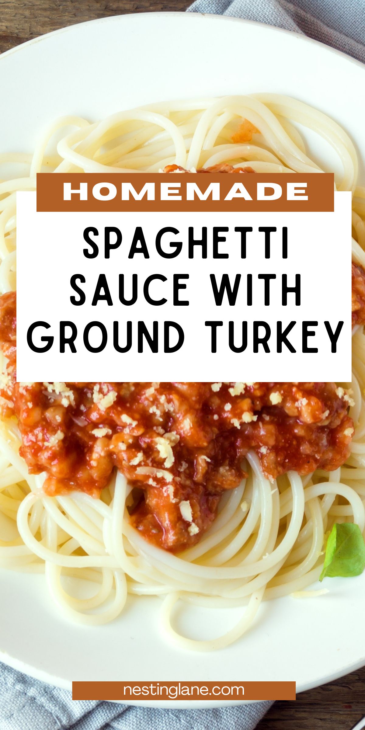 Plate of spaghetti topped with homemade spaghetti sauce made with ground turkey, chunky tomato meat sauce, and a sprinkle of grated Parmesan. White plate on a rustic table with a cloth napkin. Text overlay reads “Homemade Spaghetti Sauce With Ground Turkey” and “nestinglane.com.”