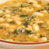 Creamy white bean and kale soup in a ceramic bowl, with tender white beans, chopped kale, and a light golden broth. Hearty vegetable soup with a smooth texture, visible greens, and beans throughout, served warm on a wooden table for a cozy, healthy meal.
