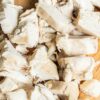 Close-up overhead of chopped, shredded cooked chicken breast on a wooden cutting board, moist white meat ready for salads, soups, or high-protein Instant Pot recipes.