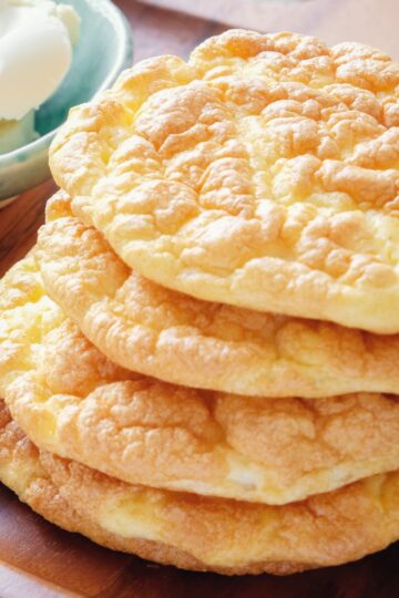 Stack of homemade low carb cloud bread rounds with a fluffy, airy texture and lightly golden tops, resting on a wooden surface. Soft, pillowy bread made with simple ingredients, showing a cloud-like interior and delicate browned edges, styled for healthy Weight Watchers friendly baking.