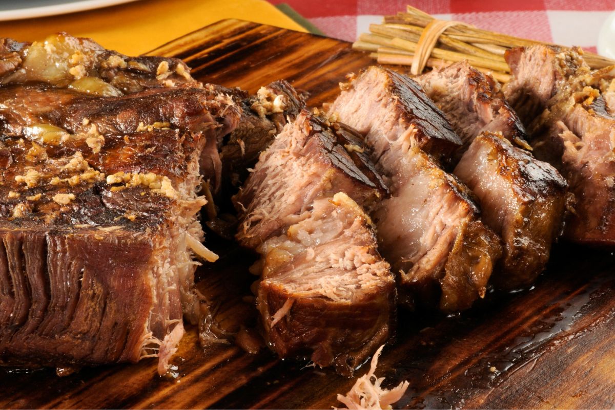 High protein crockpot Italian beef roast sliced on a wooden cutting board, showing tender, juicy beef with browned edges and rich cooking juices. Slow cooker beef roast with visible texture and savory finish, ready for serving.