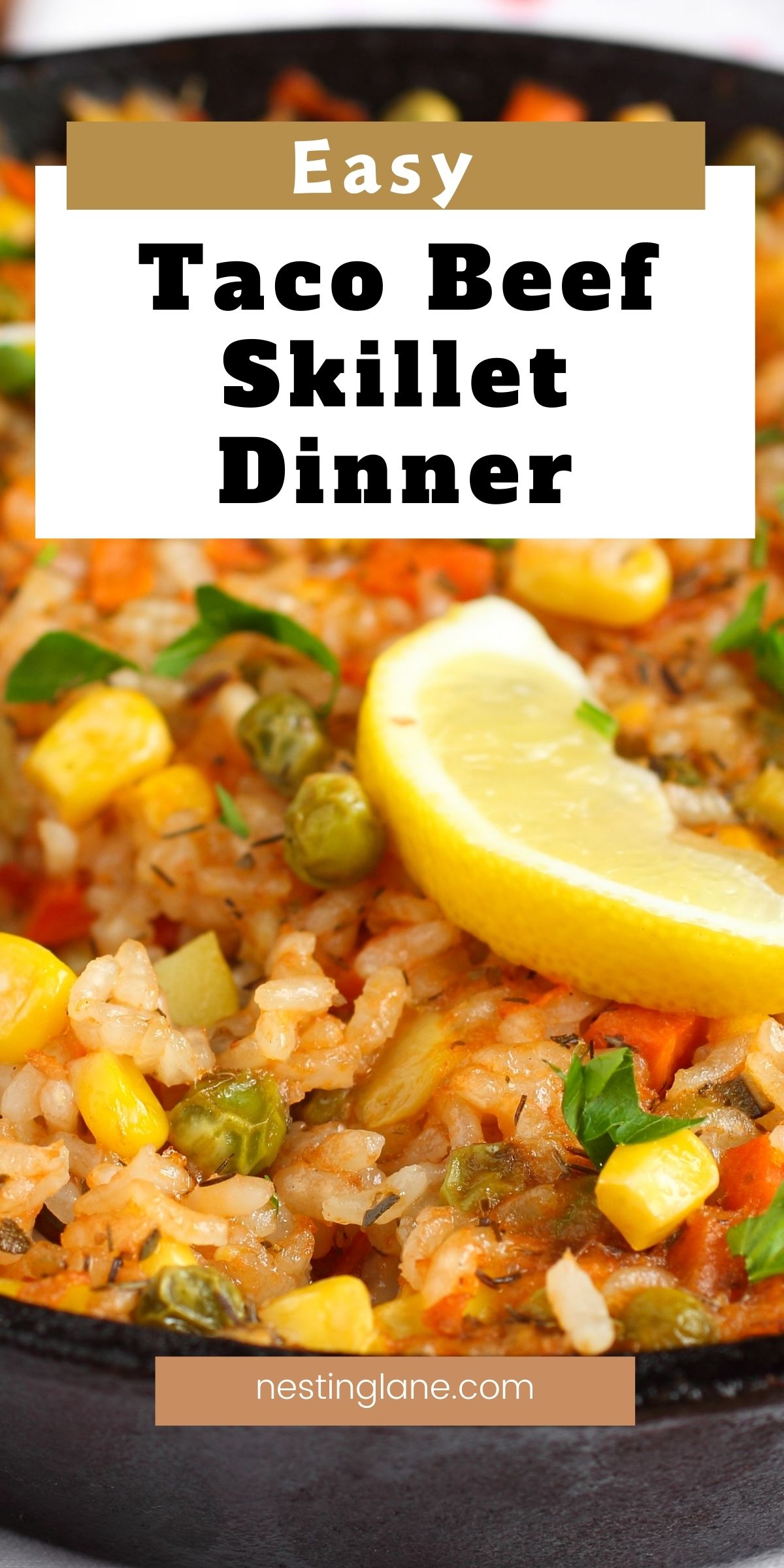 Skillet taco beef dinner with rice, corn, peas, carrots, herbs, and a lemon wedge in a black pan. Overlay text reads “Easy Taco Beef Skillet Dinner” in bold black on a white box with a tan header. Bottom text says “nestinglane.com”.