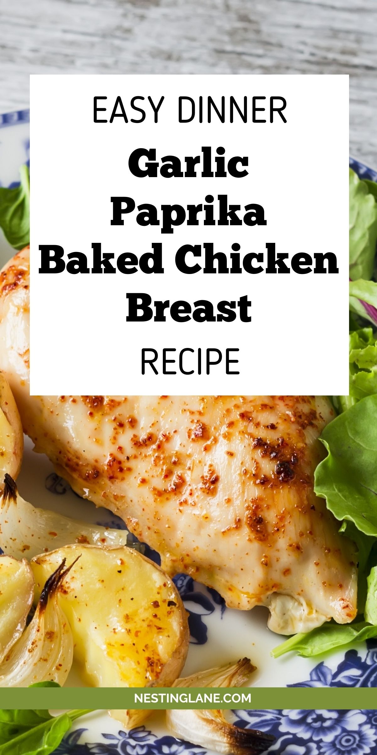 Garlic paprika baked chicken breast on a blue and white plate with roasted potato wedges, roasted garlic cloves, and fresh lettuce. Overlay text reads “EASY DINNER Garlic Paprika Baked Chicken Breast RECIPE.” Bottom text says “NESTINGLANE.COM”.