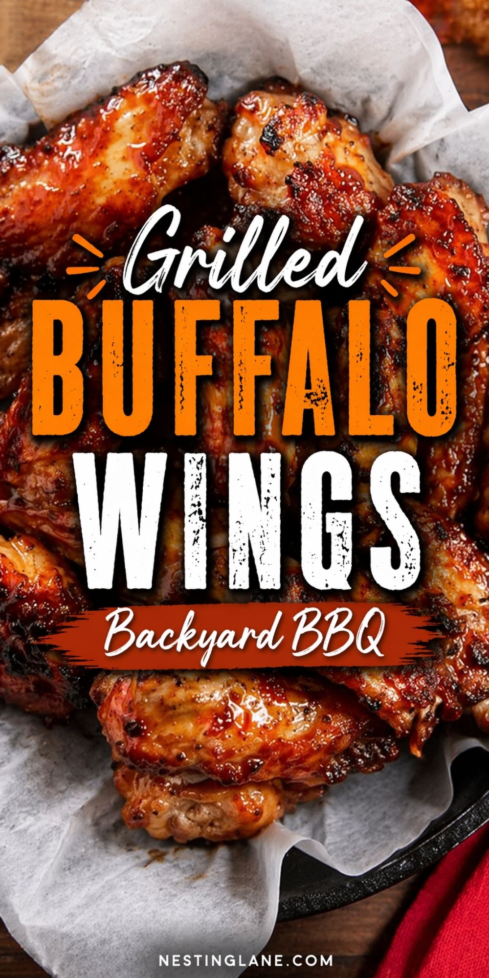 Grilled buffalo wings coated in glossy sauce on parchment paper in a black skillet. Large text reads “Grilled Buffalo Wings” and “Backyard BBQ.” Bottom text reads “nestinglane.com.”