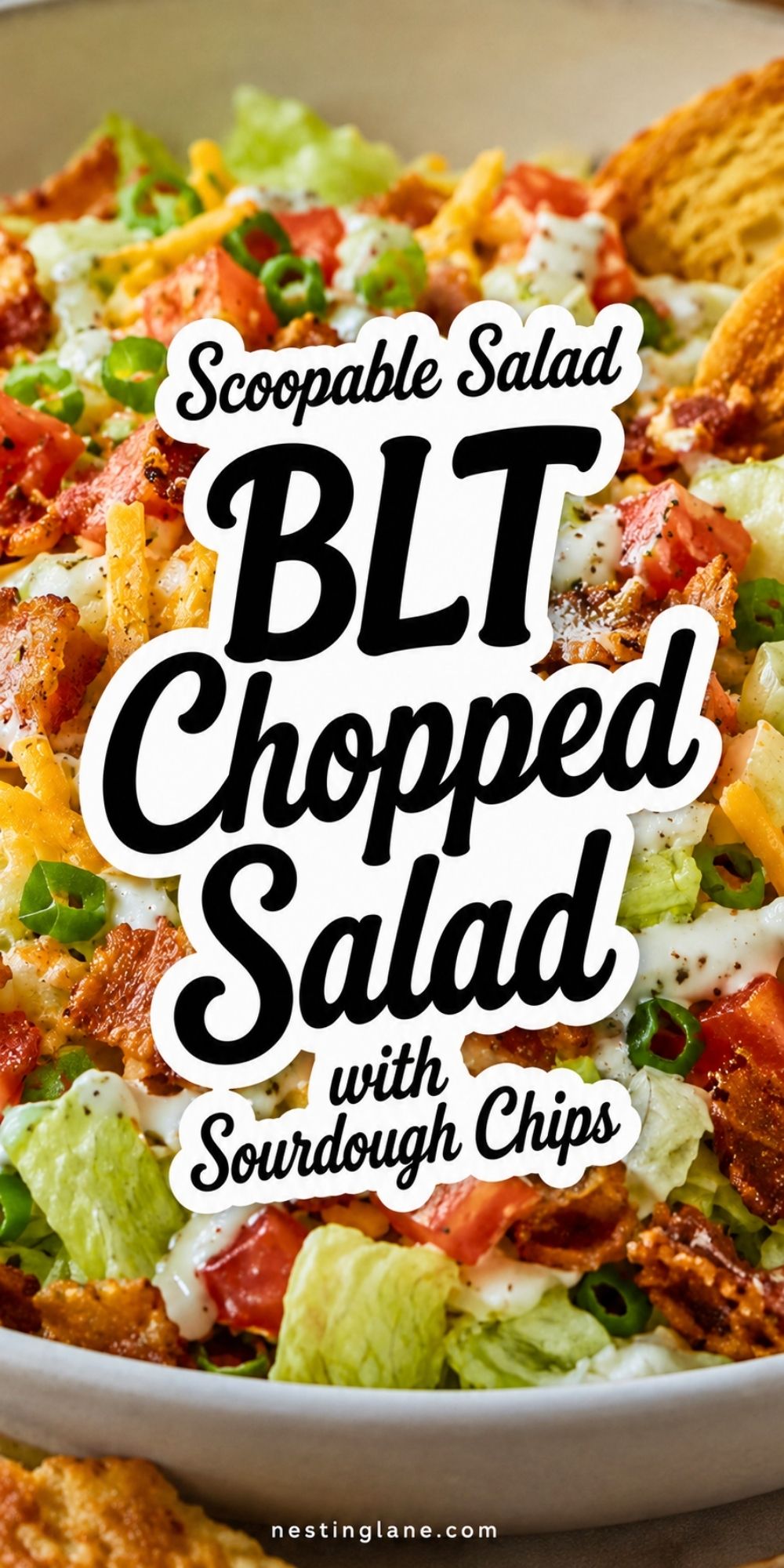 BLT chopped salad with iceberg lettuce, tomatoes, bacon, green onions, cheddar cheese, creamy ranch dressing, and toasted sourdough chips in a bowl. Text reads “Scoopable Salad BLT Chopped Salad with Sourdough Chips” and “nestinglane.com.”