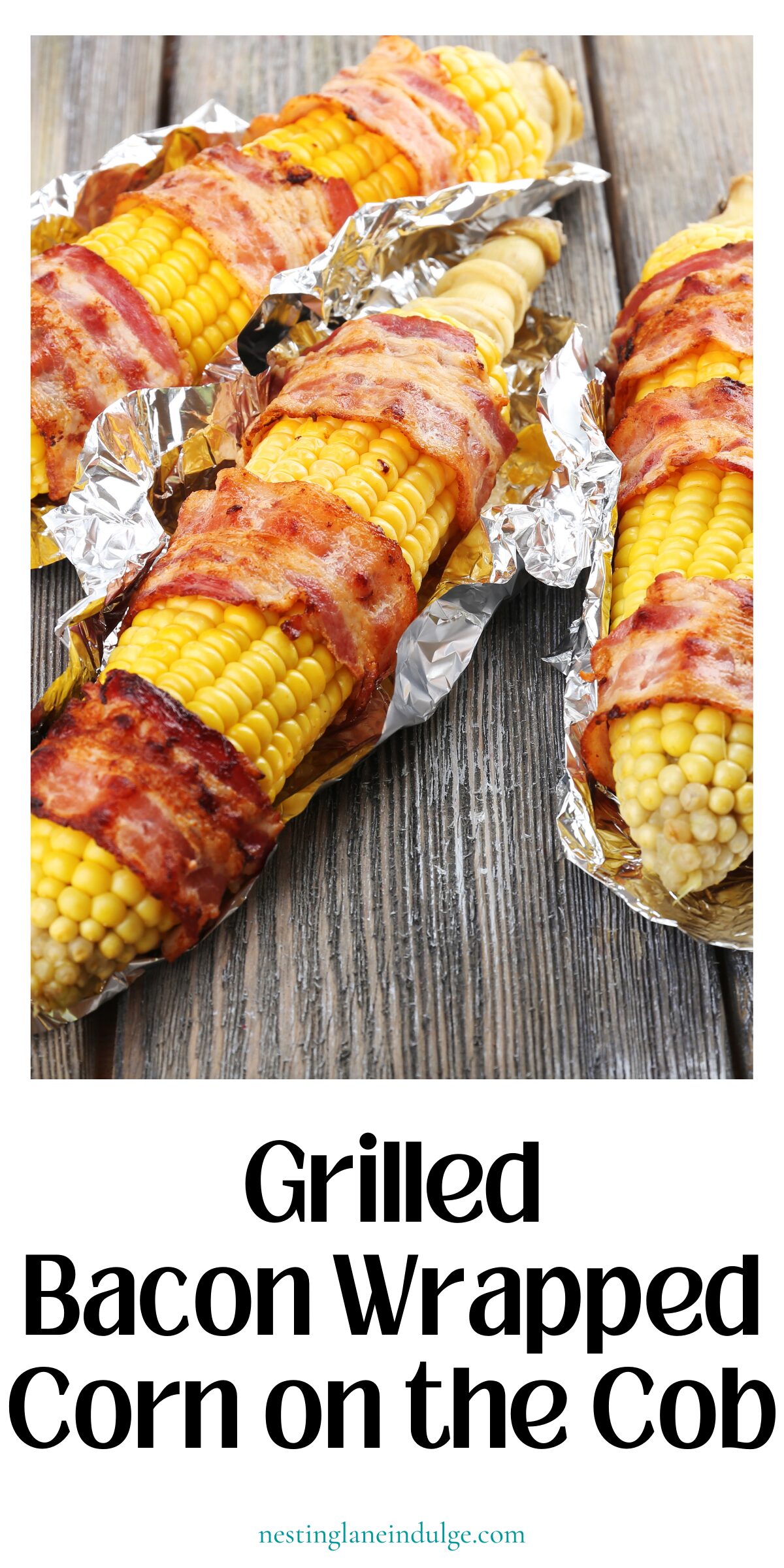Grilled bacon wrapped corn on the cob in foil on a wooden table. Text reads “Grilled Bacon Wrapped Corn on the Cob” and “nestinglaneindulge.com.”
