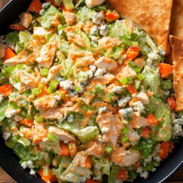 Buffalo chicken chopped salad with lettuce, celery, red bell peppers, blue cheese crumbles, creamy Buffalo dressing, and crispy chips.