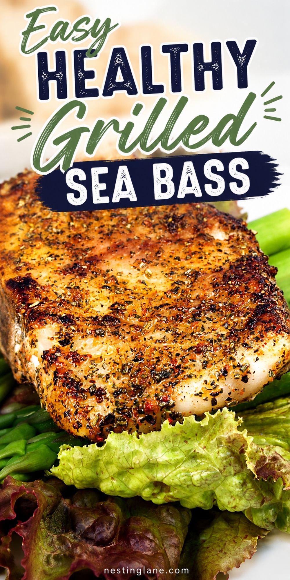 Easy healthy grilled sea bass with a golden herb crust, served over asparagus and leafy greens on a white plate. Text reads “Easy Healthy Grilled Sea Bass” with “nestinglane.com” at the bottom.
